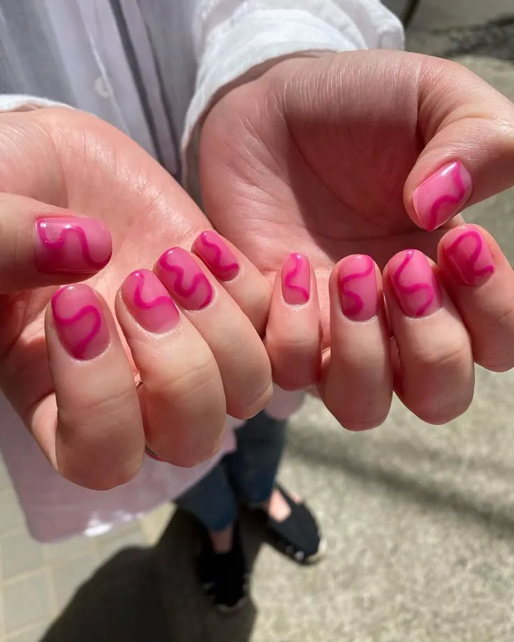 Hot pink nails with a squiggle design
